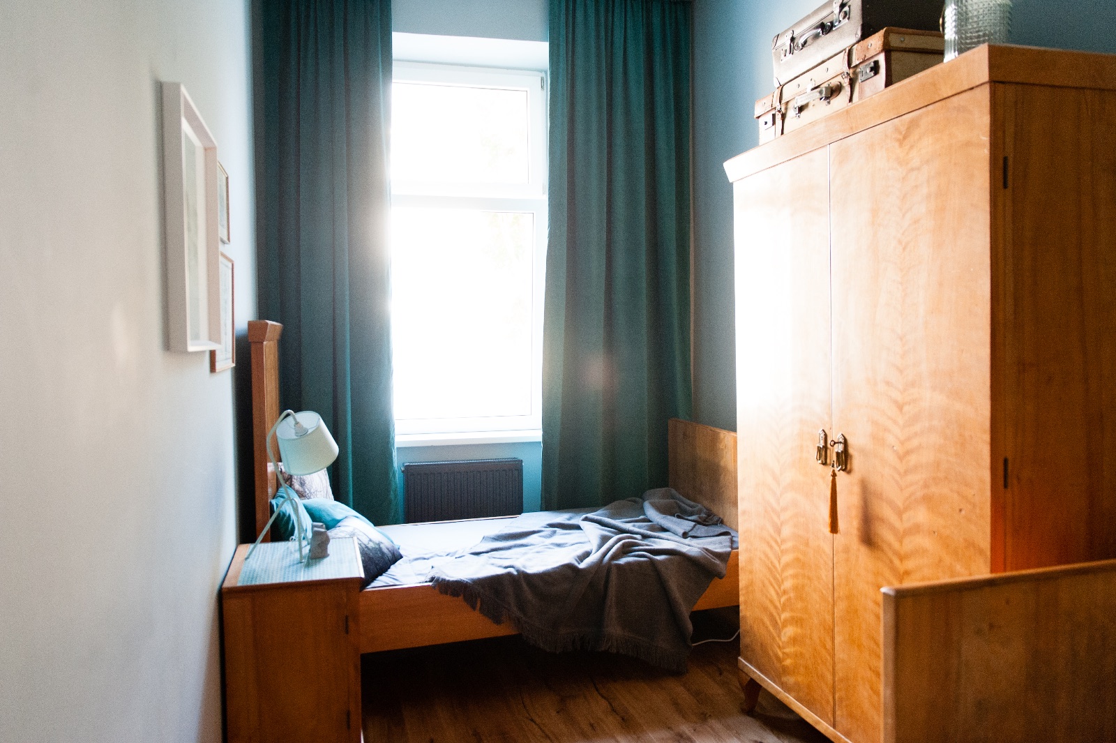 Wohnraum mit türkisem Vintage-Schrank, hellgrauem Esstisch auf Eichenbeinen und Sofa, daneben zwei Schlafzimmer für eine Familie auf Zeit in Wien