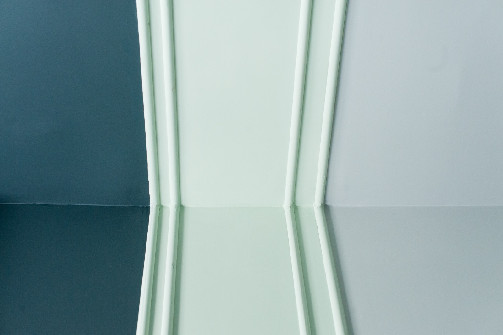 Appartement meublé à Vienne pour une durée déterminée avec rideaux bleu nuit, lit à la couverture vert menthe et armoire en ronce de bois portant un vieux globe