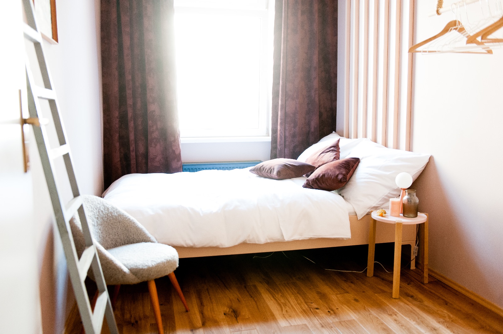 Espace de vie avec une armoire vintage turquoise, une table à manger gris clair sur des pieds en chêne et un canapé, à côté deux chambres pour une famille à Vienne pour un temps