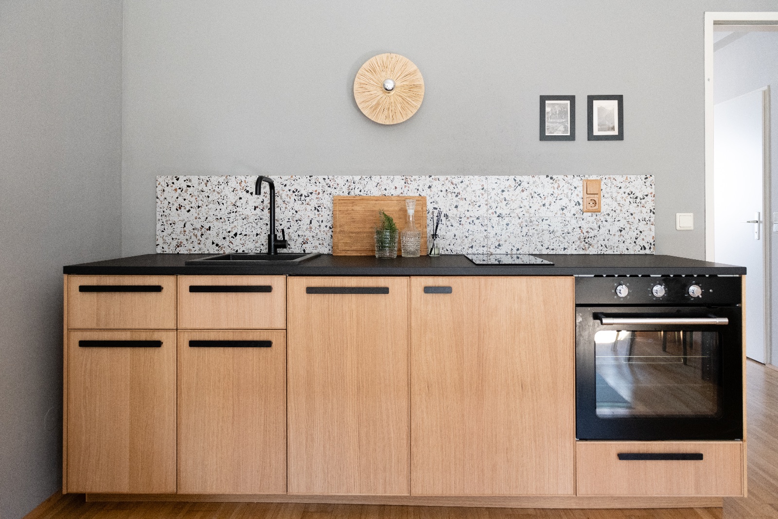 Dining table of smoke grey glass with walnut chairs, pale oak kitchen with terrazzo and white tiled bathroom in a furnished apartment in Vienna