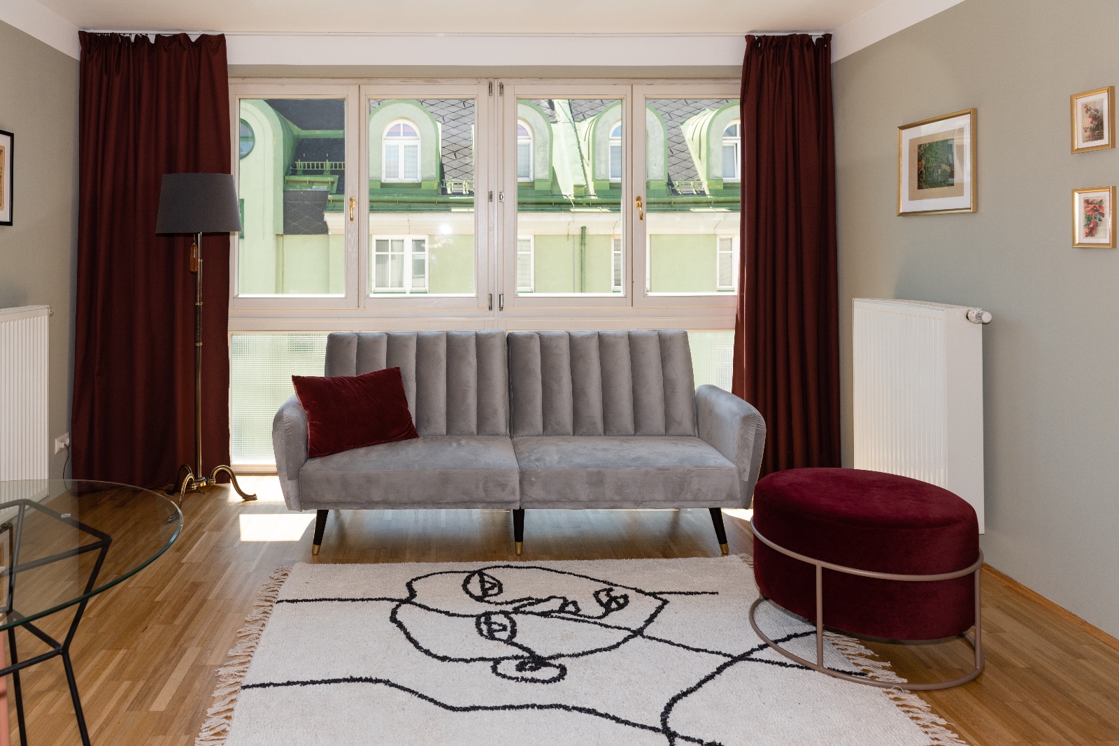Appartement meublé à Vienne, chambre avec lit en lin et suspension, couloir au papier peint de bouleau et miroir, séjour avec canapé de velours gris à la fenêtre