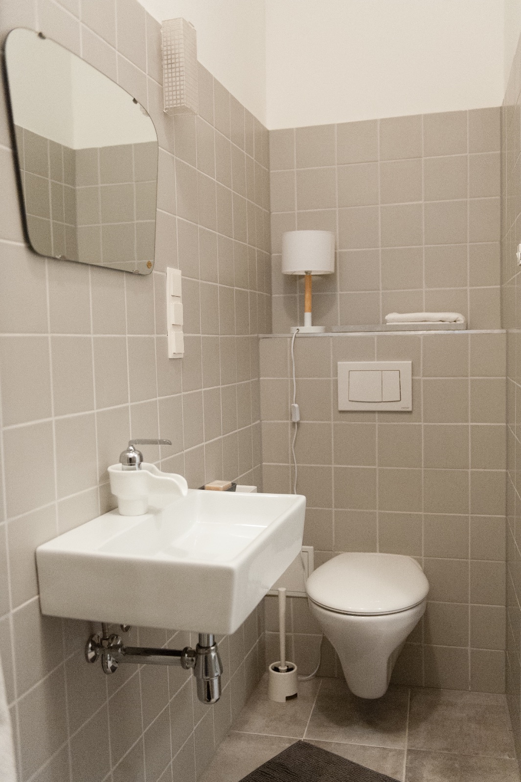 Helles Vorzimmer einer möblierten Zwischenmiete in Wien mit hölzernen Kleiderbügeln, weißer Konsole und Betonschale
