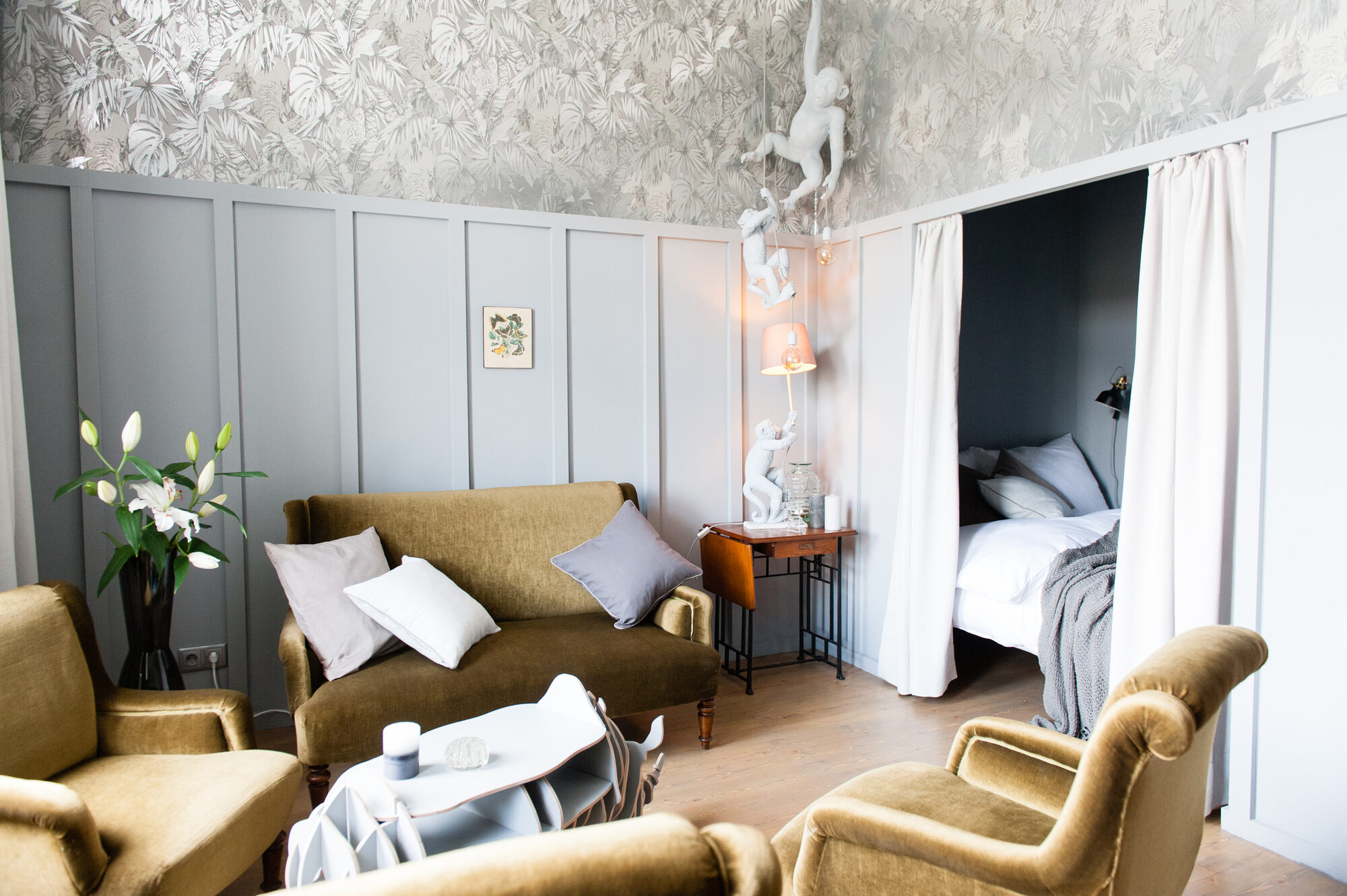 LAROGY Apartment Vienna — living room with olive velvet armchairs, alcove bed and Seletti monkey lamps